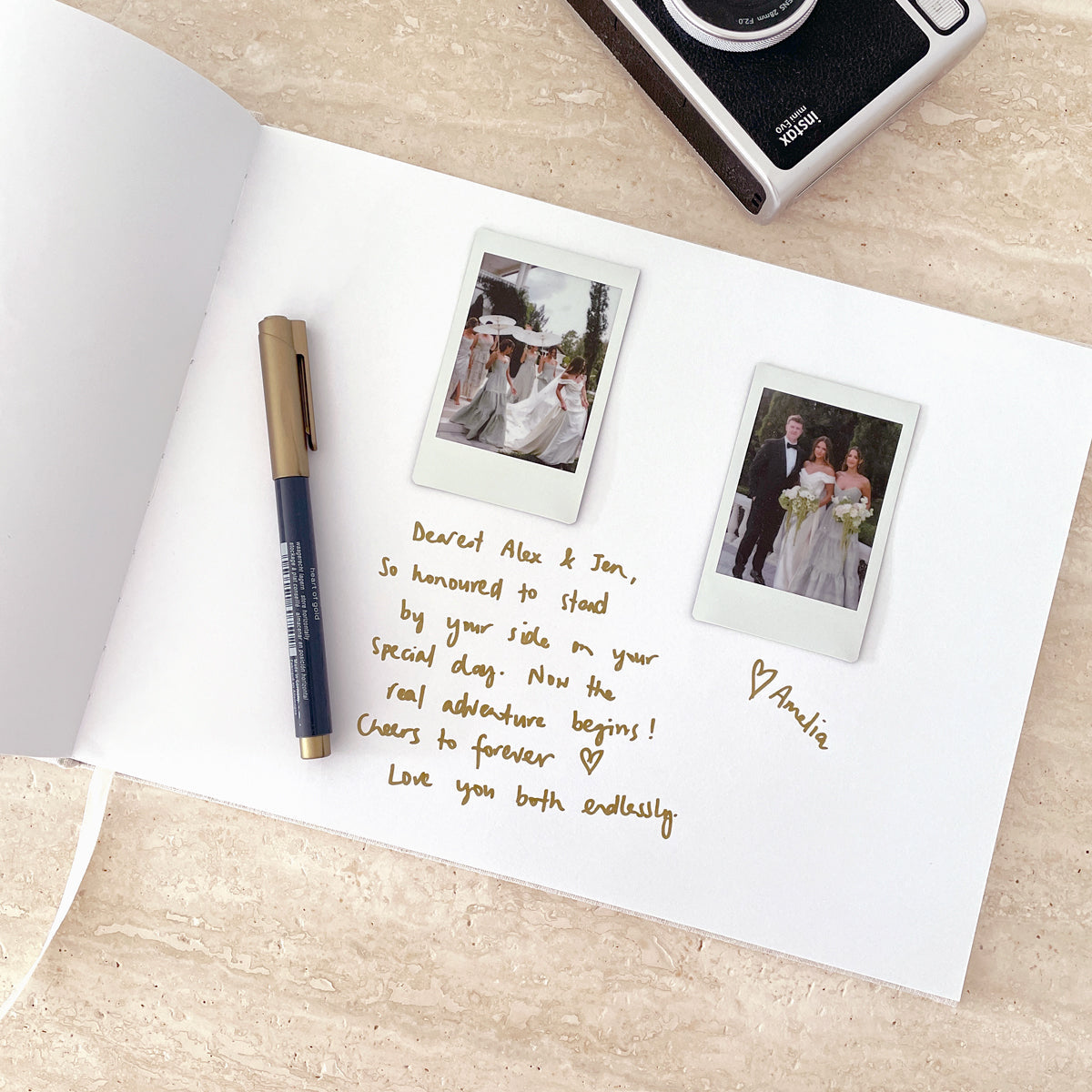 Open book with handwritten note, two Polaroid photos, and a camera on a wooden surface.
